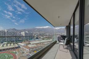 A balcony with a chair and a view of a city and mountains.
