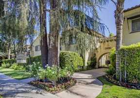 the front of a house with trees and a sidewalk