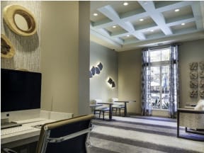 a room with a computer desk chairs and a window