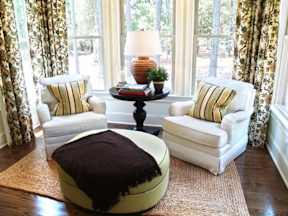 a living room with two chairs and a ottoman in front of a window