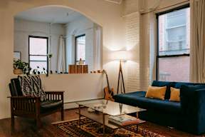 A living room with a guitar on the wall and a blue couch.