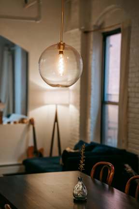 A table with a vase on it and a light bulb hanging from the ceiling.