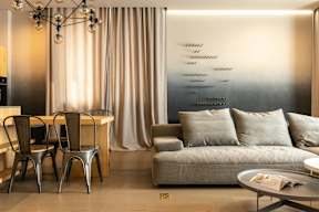 A modern living room with a grey couch, a wooden table, and a metal chair.
