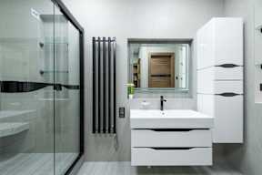 A modern bathroom with a white sink and a glass shower.