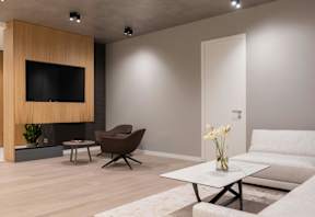 A modern living room with a flat screen TV, a brown chair, a white sofa, and a coffee table.