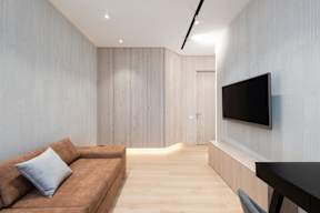 A modern living room with a brown couch and a flat screen TV mounted on the wall.