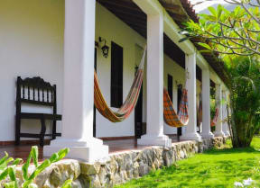 a porch with hammocks and chairs outside of a house