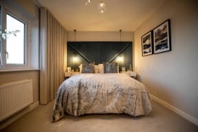 the master bedroom has a large bed and a black and white headboard