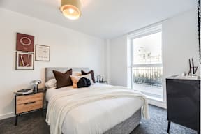 A bedroom with a large bed and a window overlooking a balcony.