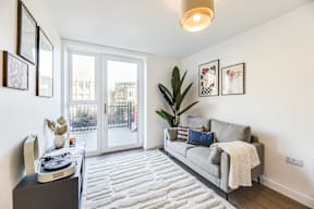 A living room with a grey couch, a white rug, and a record player.
