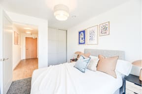 A bedroom with a bed, nightstand, and artwork on the wall.