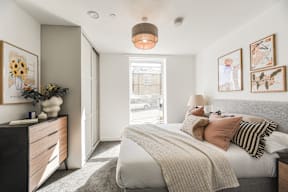 A bedroom with a large bed and a dresser with a vase of flowers on top.