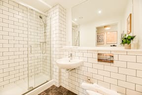 A white tiled bathroom with a glass shower door.