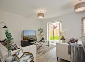 A living room with a white couch, a television, and a plant.