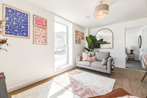 A living room with a grey couch and a large window.