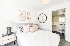 A bedroom with a white bed and a mirror on the wall.