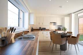 A modern kitchen with a wooden countertop and a dining table with chairs.