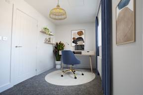 A room with a blue chair and a white desk.
