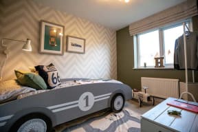 a bedroom with a bed and a toy car in it