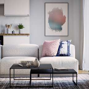 A living room with a white couch and a large abstract painting on the wall.