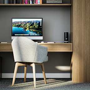 A computer monitor is on a desk with a chair in front of it.
