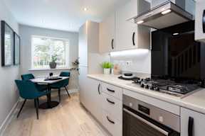 A kitchen with a dining table and chairs.