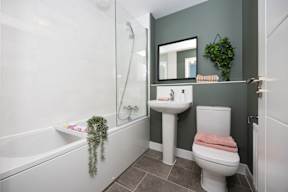 A bathroom with a white tub, sink, and toilet.