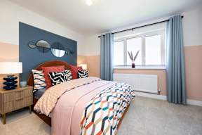 A bedroom with a bed, nightstand, and window.