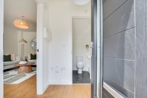 a bathroom with a toilet and a living room with a couch and a table