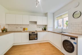 a kitchen with white cabinets and a washing machine in it