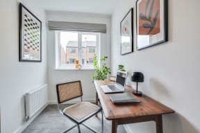 a desk with a laptop on it in a room with a window