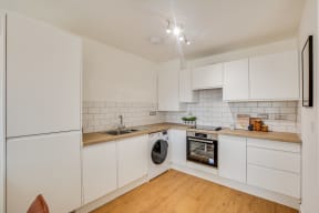 a kitchen with white cabinets and appliances and a washing machine