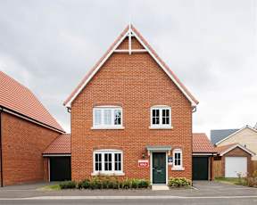 A red brick house with a green door and a red "SOLD" sign in front.