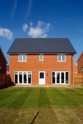 A red brick house with a black roof and a white door.