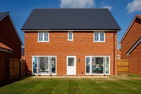 A red brick house with a black roof and white windows.