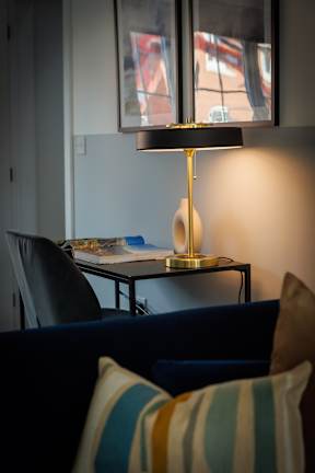A lamp with a yellow lampshade is on a table in a room.