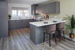 A modern kitchen with a marble countertop and grey cabinets.