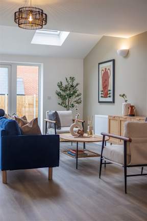 A living room with a blue couch, a chair, a small table, and a potted plant.
