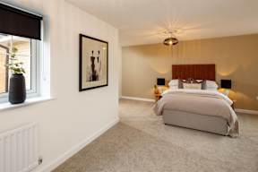 A bedroom with a large bed and a framed picture on the wall.