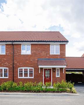 A red brick house with a red door and white windows.