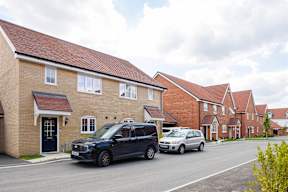A black car is parked in front of a house.