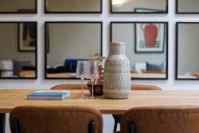 A table with a book, a glass, and a vase on it.