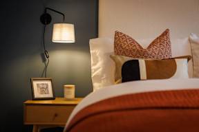 A bed with a red pillow and a white pillow with a pattern on it.