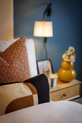 A couch with a pillow and a lamp on a side table.