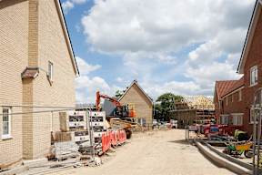 A construction site with a red excavator and a building under construction.