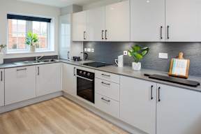 A modern kitchen with white cabinets and a wooden cutting board.