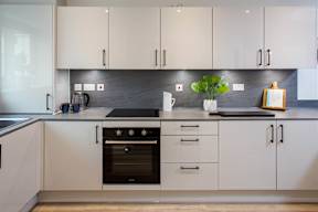 A modern kitchen with white cabinets and a black countertop.