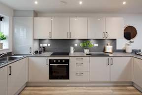 A modern kitchen with white cabinets and a black oven.