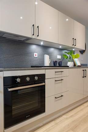 A modern kitchen with a black oven and white cabinets.