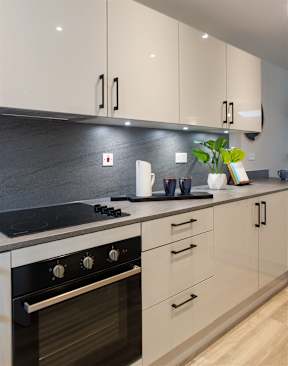 A modern kitchen with a black stove top and white cabinets.